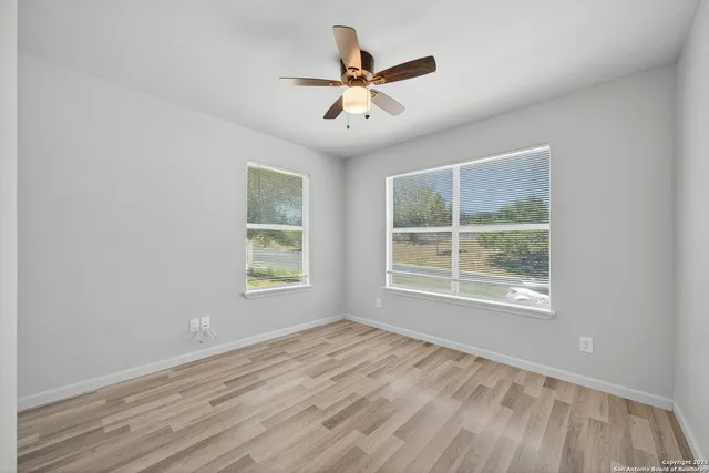 a view of an empty room with wooden floor and a window