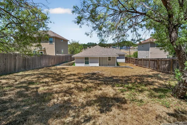 a front view of a house with a large tree and wooden fence