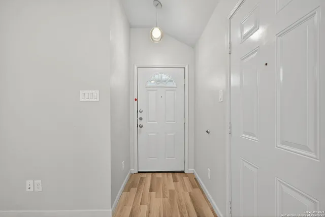 a view of a hallway with wooden floor and a bathroom