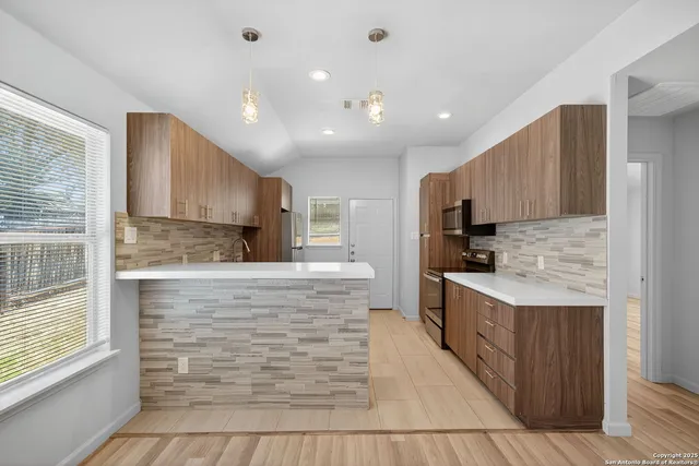 a large kitchen with kitchen island granite countertop a stove top oven a sink a counter space and cabinets