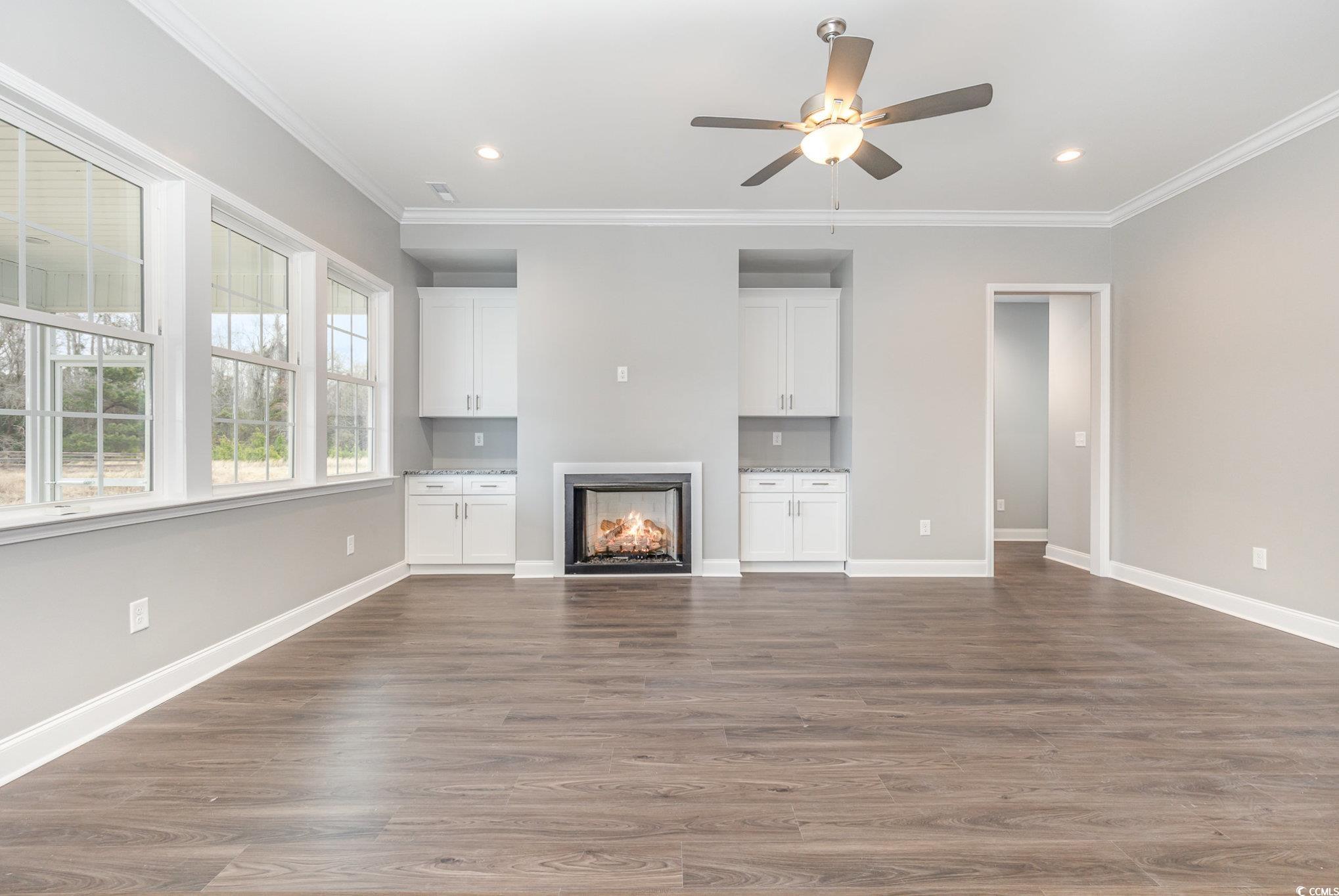 2104 Highway 9 Business Loris, SC 29569 - Photo 4 of 20 Unfurnished living room featuring a lit fireplace, dark wood-style floors, crown molding, a ceiling fan, and recessed lighting