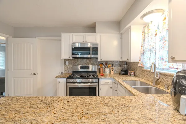 a kitchen with stainless steel appliances granite countertop a sink stove and refrigerator