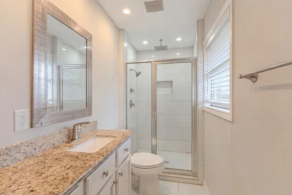 a bathroom with a granite countertop sink toilet and shower