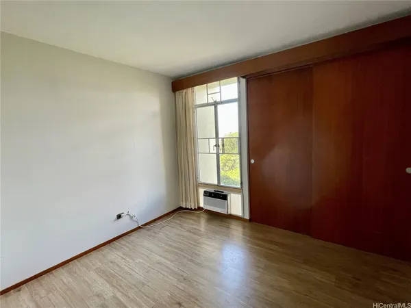 a view of an empty room with wooden floor and a window