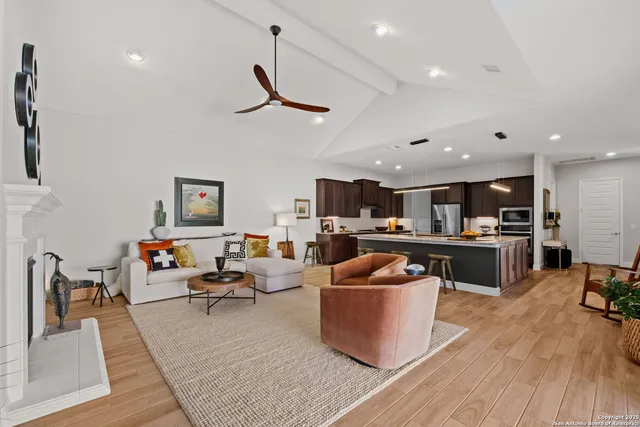 a living room with furniture kitchen view and a wooden floor