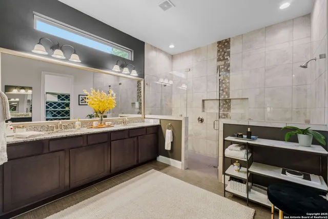 a spacious bathroom with a double vanity sink a mirror and a shower