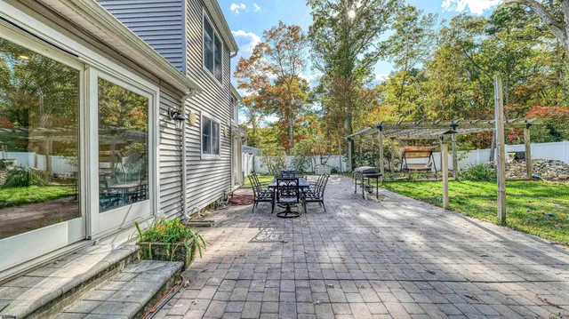 a view of a patio with table and chairs potted plants and large tree