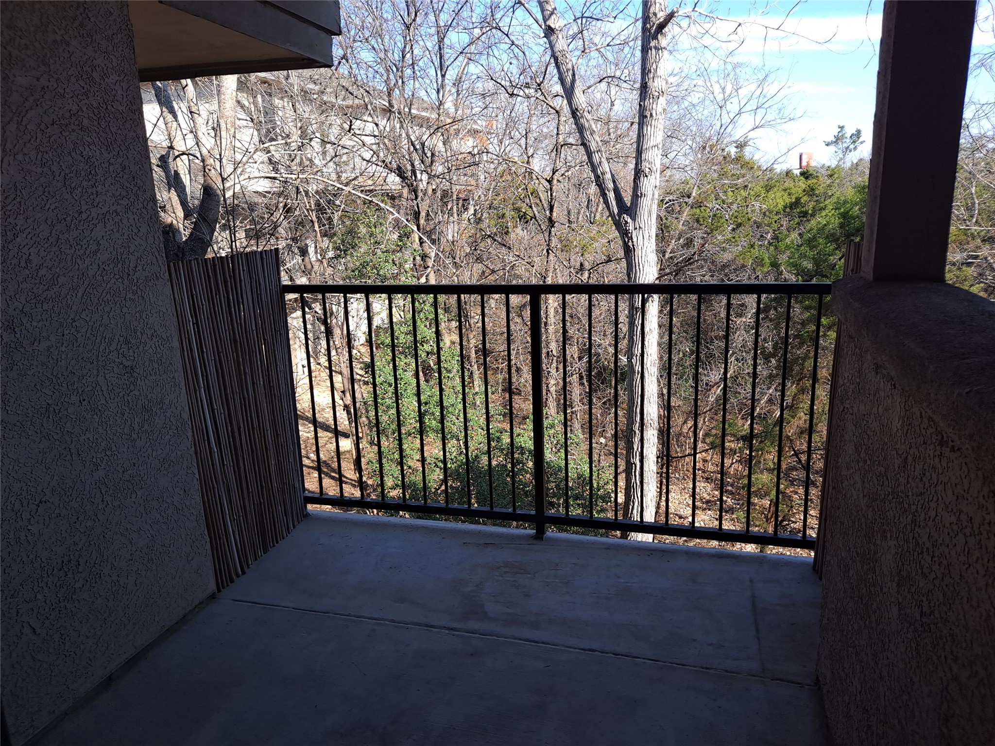 11203 Ranch Road 2222, Unit 2404 Austin, TX 78732 - Photo 8 of 28 Private balcony featuring concrete flooring, black metal railings, and a natural tree-lined backdrop