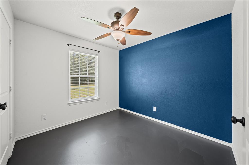 229 Firefly Drive Springtown, TX 76082 - Photo 16 of 33 Room with a dark accent wall, a window with blinds, and dark flooring