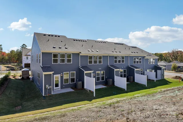 a front view of residential houses with yard and road