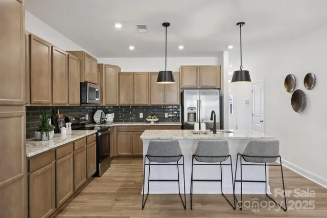 a kitchen with stainless steel appliances granite countertop a stove top oven a sink dishwasher and white cabinets with wooden floor