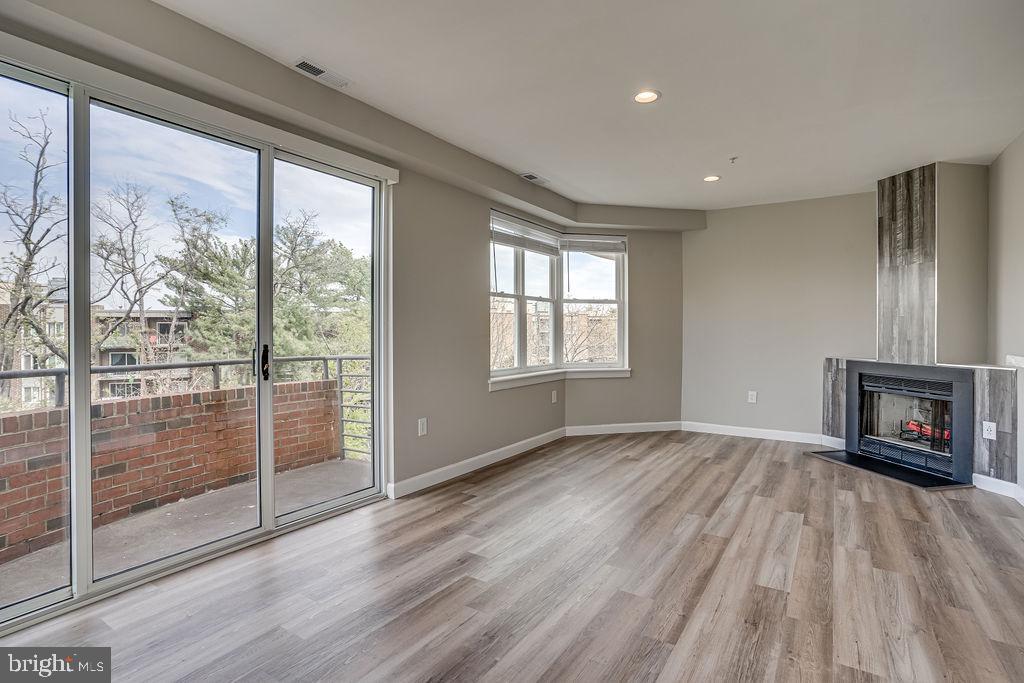 301 South Reynolds Street, Unit 607 Alexandria, VA 22304 - Photo 1 of 16 an empty room with wooden floor fireplace and windows