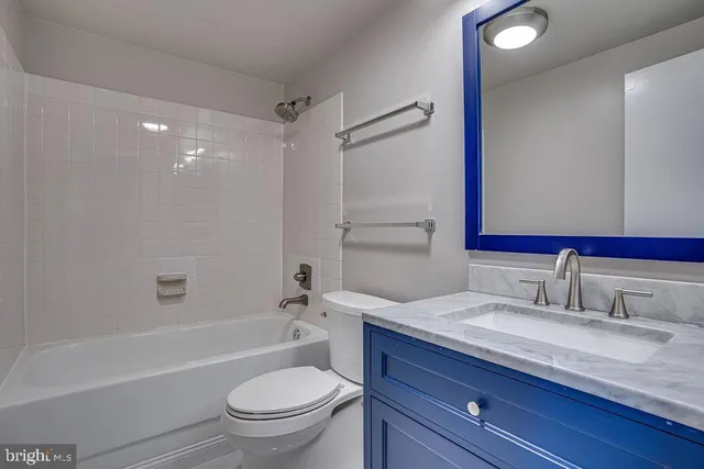 a bathroom with a granite countertop sink a toilet and a bathtub