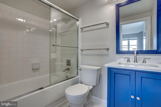 a bathroom with a toilet sink vanity granite and shower