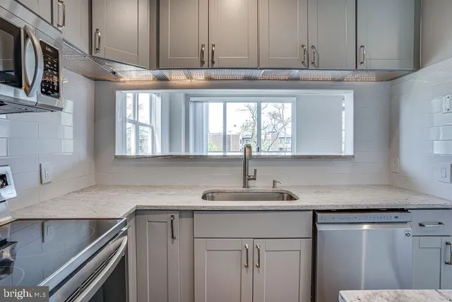 a kitchen with stainless steel appliances granite countertop a sink and a stove