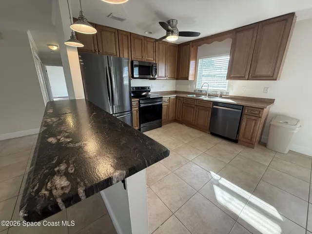 a kitchen with granite countertop a stove a sink and a refrigerator