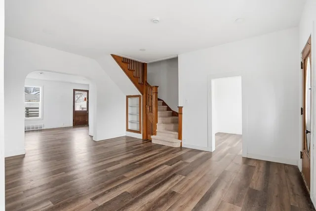 a view of a hallway with wooden floor and stairs