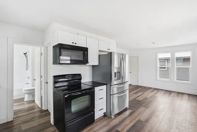 a kitchen with stainless steel appliances a stove a microwave and a hard wood floors
