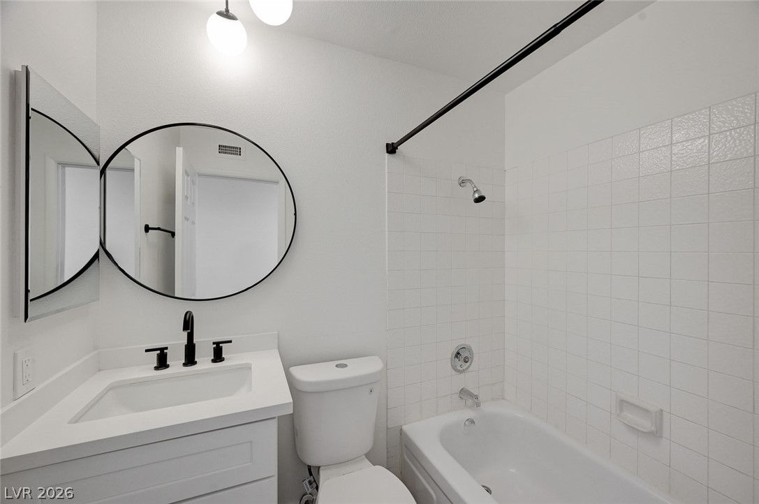 4840 Summerhill Road Las Vegas, NV 89121 - Photo 24 of 56 A pristine bathroom featuring a clean vanity with a modern mirror and a classic tiled shower-tub combination.
