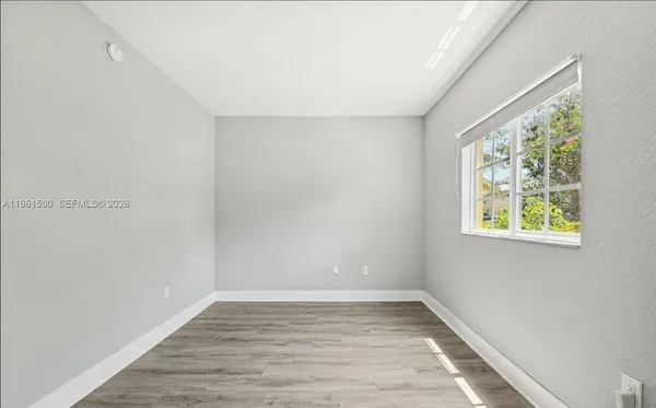 a view of an empty room with wooden floor and window