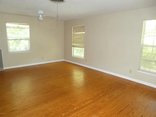 an empty room with wooden floor and windows