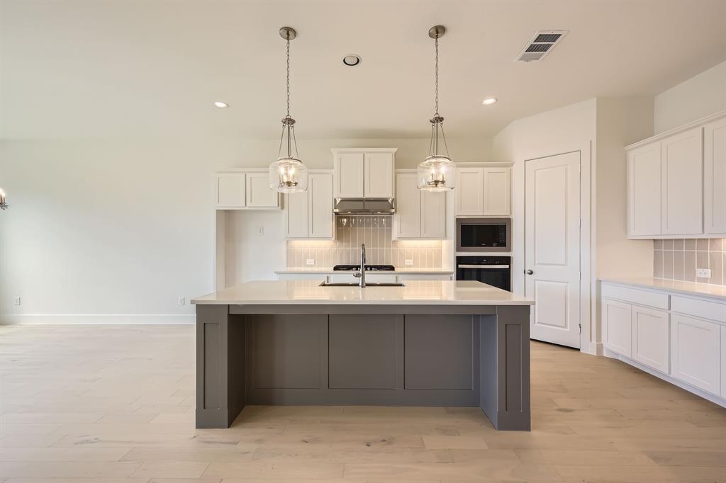 167 Sandie Drive Rhome, TX 76078 - Photo 8 of 29 Kitchen featuring black oven, stainless steel microwave, tasteful backsplash, white cabinets, and recessed lighting