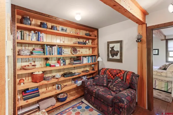 a living room with furniture and a bookshelf with wooden floor