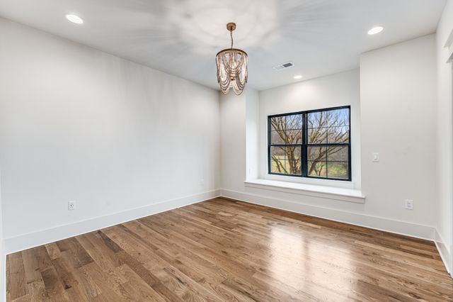 an empty room with wooden floor ceiling fan and windows