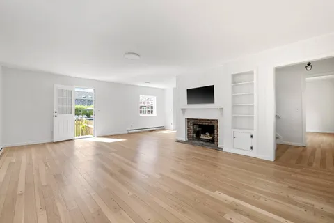 wooden floor fireplace and windows in an empty room