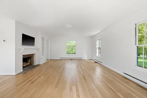 a view of empty room with wooden floor and fireplace