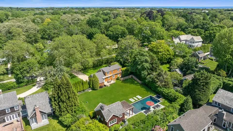 an aerial view of a residential houses with outdoor space and trees