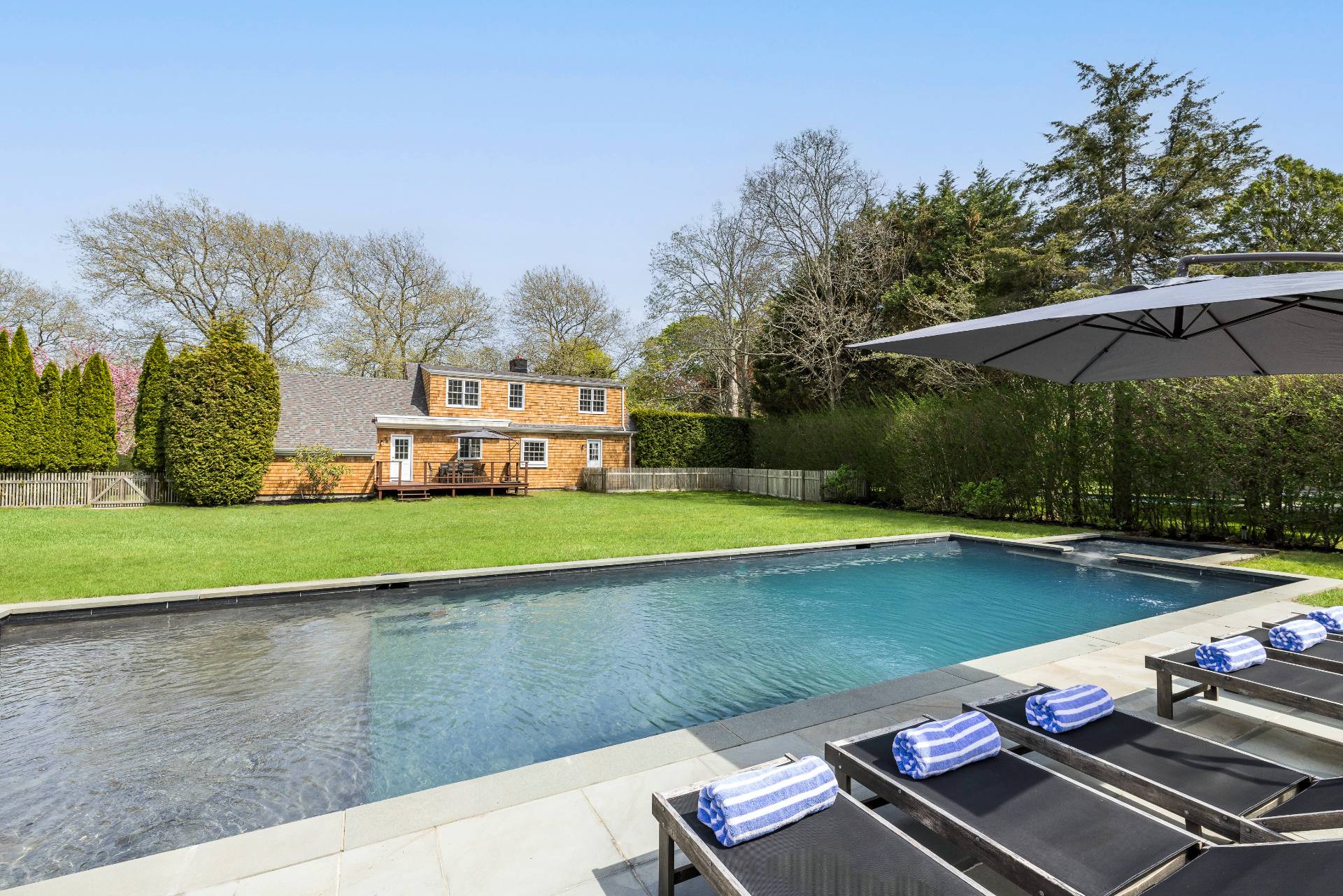 96 Audubon Avenue Bridgehampton, NY 11932 - Photo 7 of 25 a view of a swimming pool with lawn chairs under an umbrella