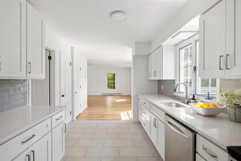 a large white kitchen with stainless steel appliances granite countertop a lot of counter space and wooden floor