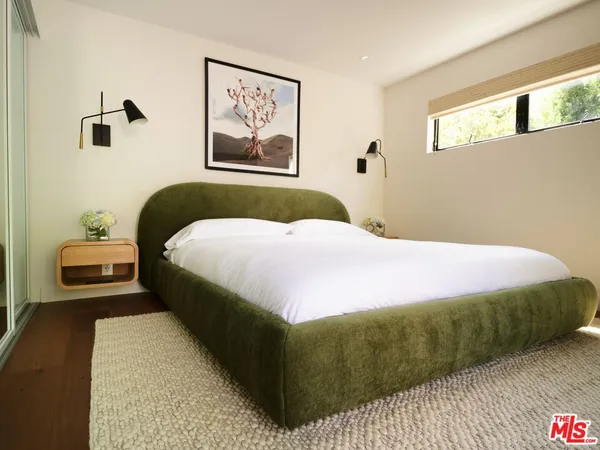 a bedroom with a bed and painting on the wall