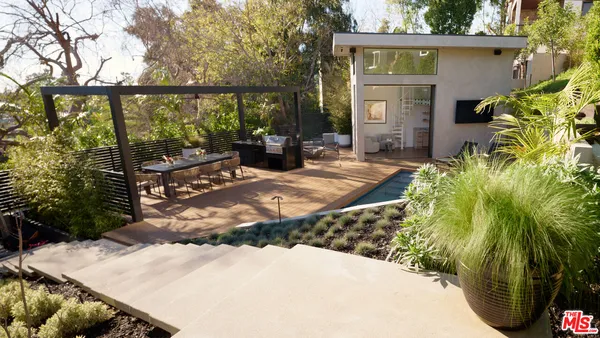a view of a backyard house with large trees and plants