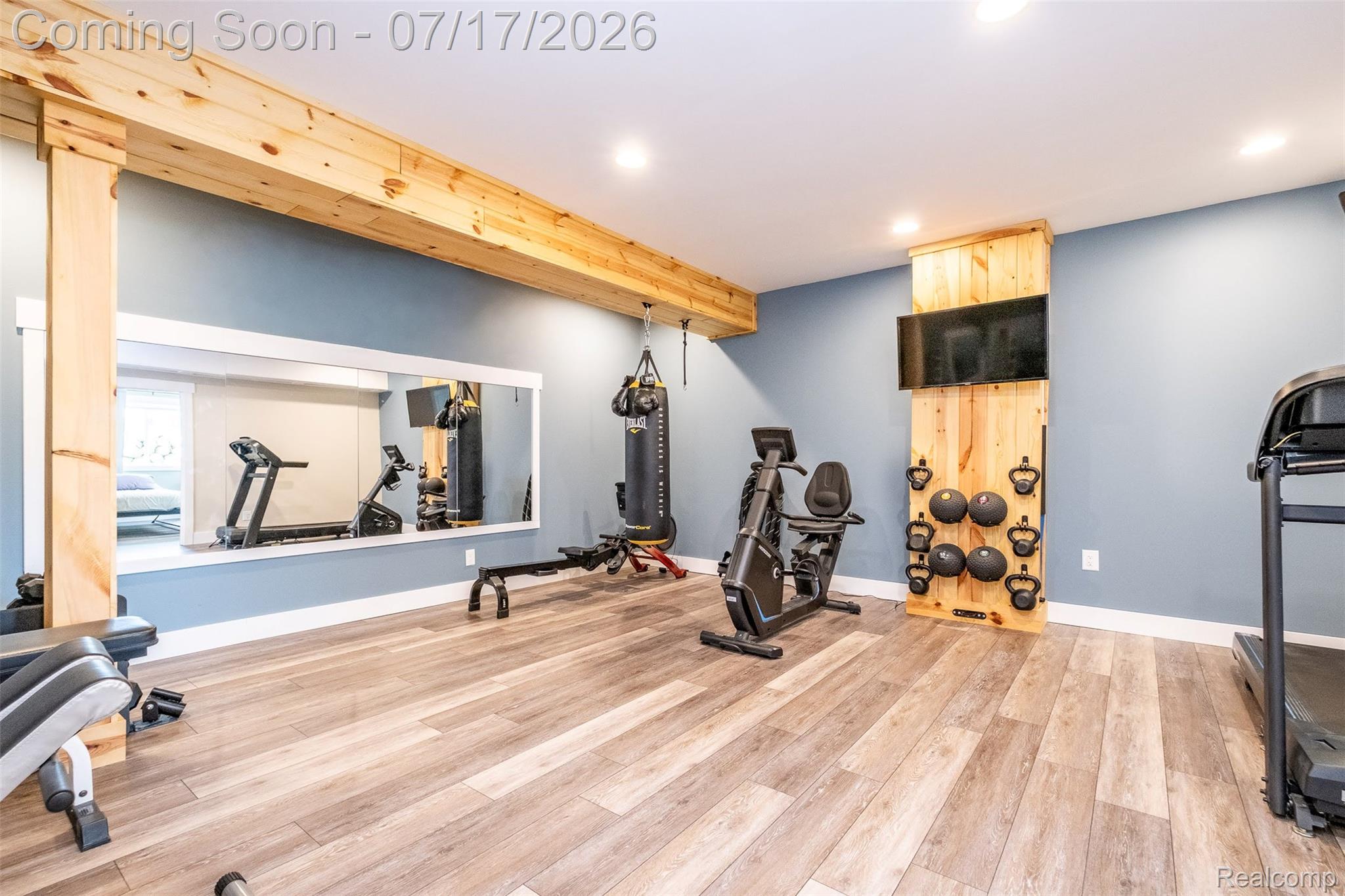 12349 Sugar Maple Drive Fenton, MI 48430 - Photo 40 of 67 Recreational space featuring wood-finish flooring, exposed wood beams, and a built-in wood wall panel with integrated media display