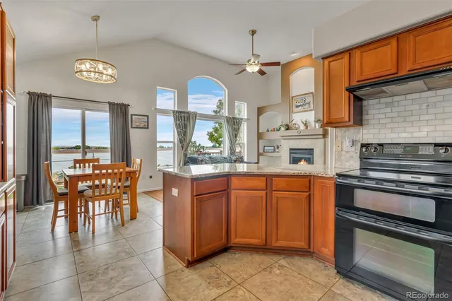 a kitchen with stainless steel appliances granite countertop a stove top oven a sink a dining table and chairs