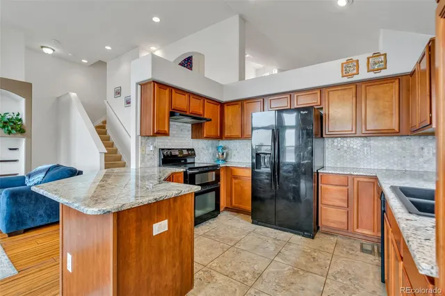 a kitchen with stainless steel appliances granite countertop a refrigerator a stove and a sink