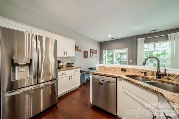 a kitchen with stainless steel appliances granite countertop a sink a stove and a refrigerator