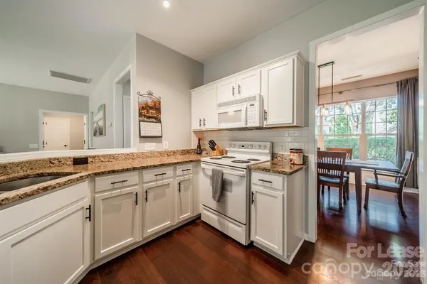 a kitchen with stainless steel appliances granite countertop a stove and white cabinets