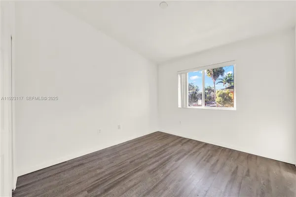 an empty room with wooden floor and window