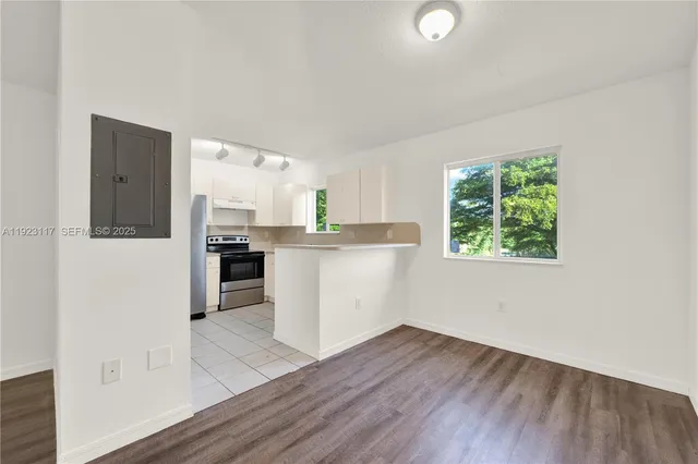 a kitchen with stainless steel appliances granite countertop a refrigerator a sink dishwasher a stove and white countertops with wooden floor