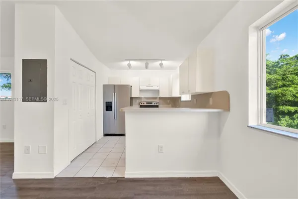 a kitchen with stainless steel appliances granite countertop a refrigerator sink and white cabinets