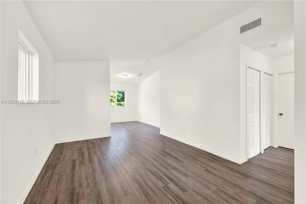 an empty room with wooden floor and windows