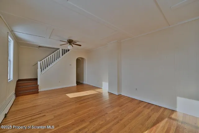 a view of an empty room with wooden floor and stairs
