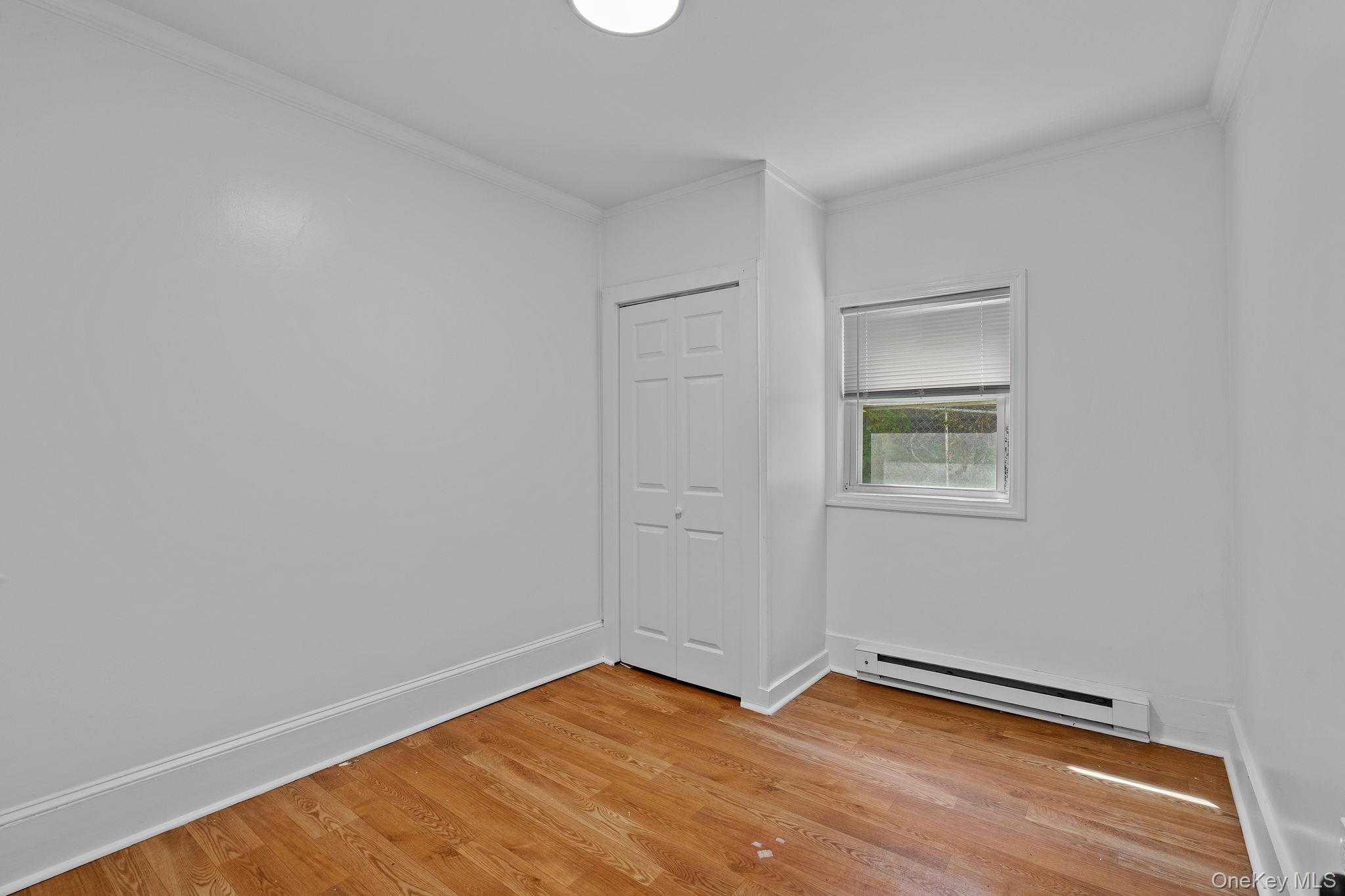 93 Delafield Street Poughkeepsie, NY 12601 - Photo 15 of 27 Spare room with baseboard heating, light wood-style flooring, and ornamental molding