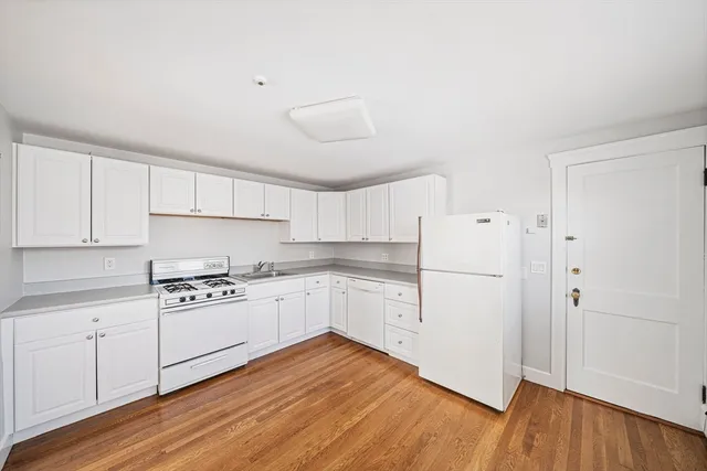a kitchen with white cabinets and wooden floor