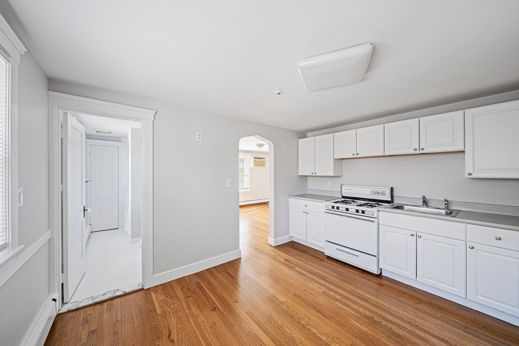 14 Hartwell Street, Unit B Waltham, MA 02453 - Photo 3 of 24 a kitchen with granite countertop white cabinets and white appliances