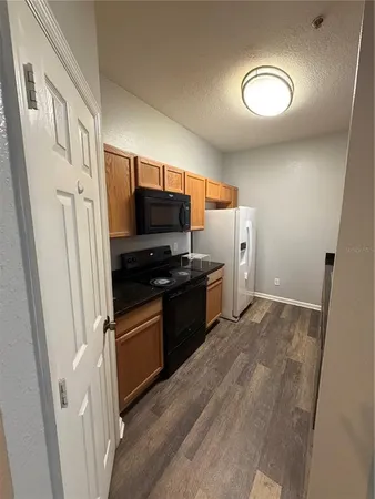 a kitchen with a refrigerator a stove and a sink with wooden floor