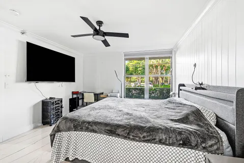 a bedroom with a bed a flat screen tv and a large window